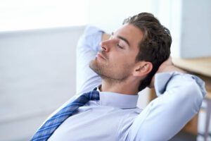 Man leaning back in his chair with hands behind his head and a peaceful expression – click to explore CBD for immune system support.