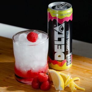 delta water can next to glass with ice and raspberry and lemons on table