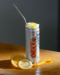 can of delta water mango with straw, gray back ground and orange and mango slices