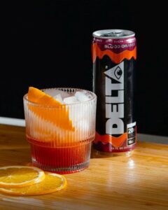 delta water can next to glass of ice with orange slices on table