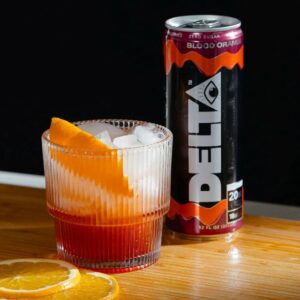 delta water can next to glass of ice with orange slices on table