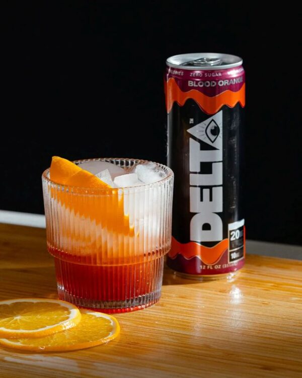 delta water can next to glass of ice with orange slices on table