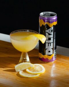 can of delta water next to glass of lemon beverage and lemon slices on table