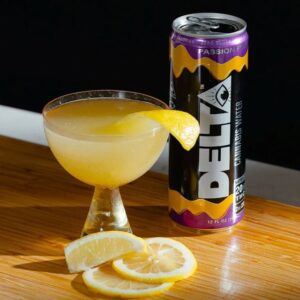 can of delta water next to glass of lemon beverage and lemon slices on table