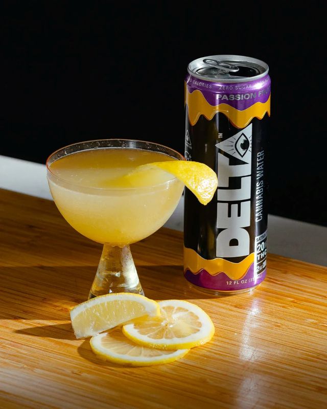 can of delta water next to glass of lemon beverage and lemon slices on table